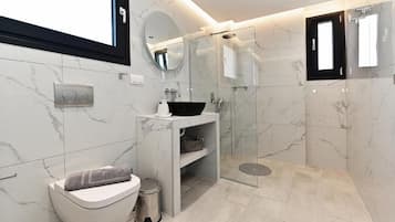 Un baño moderno con inodoro, lavabo y zona de ducha.