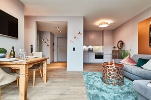 A modern living room with a dining area, a kitchen in the background, and a cozy seating area with a patterned rug. - Holiday apartment in Sylt with 1 bedroom (Westerland)