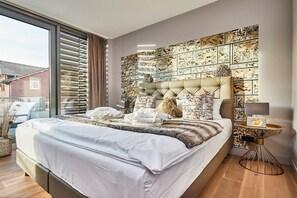 Quarto moderno com uma cama grande, cabeceira decorativa e vista para o exterior.