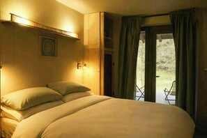 A bedroom with a bed, a wall-mounted light, and a view of the outdoors through a door. - Mountain lodge in Val di Ledro with family history (Ledro)