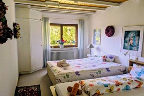 A bedroom with two beds, a window with curtains, a radiator, and a wall-mounted lamp. - Holiday home with 2 bedrooms (Herdwangen-Schönach)