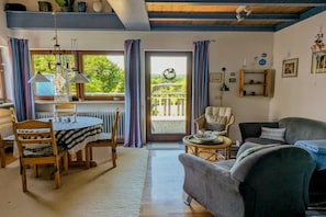 A cozy living room with a dining table, a sofa, and a balcony with curtains. - Holiday home with 2 bedrooms (Herdwangen-Schönach)