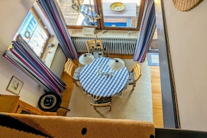 A dining area with a round table, chairs, and a window with curtains. - Holiday home with 2 bedrooms (Herdwangen-Schönach)