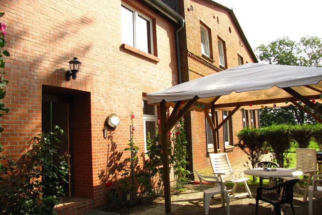 A brick building with a covered patio area featuring outdoor furniture and a white canopy.