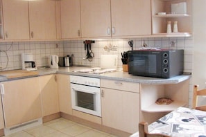 Una cocina compacta equipada con microondas, estufa y cafetera.