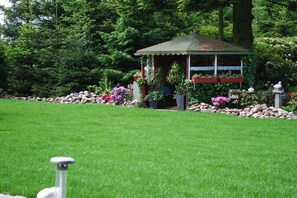 A gazebo with a tiled roof surrounded by a garden with various plants and flowers. - in Gretchen's house 2 (Südbrookmerland Ortsteil Moorhusen)