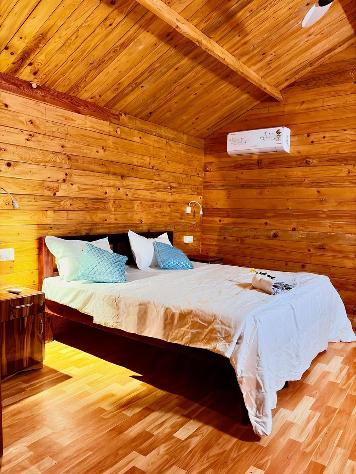 A wooden cabin room with a bed, nightstands, and a ceiling fan.