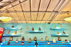 Zona de bar con estanterías llenas de botellas de licores y dos candelabros.
