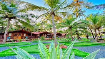 A resort with multiple wooden cabins, surrounded by palm trees and well-manicured lawns.