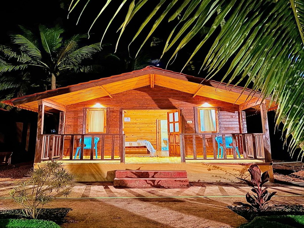 A wooden cabin with a porch, a bed, and a small table.