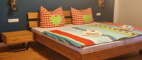 Una cama con un cojín estampado, una colcha y una mesita de noche.
