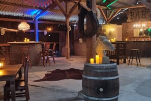 An indoor bar with wooden furniture, a bar counter, and a rustic decor including a barrel with candles. - Holiday home in Kail with swimming pool (Kail)