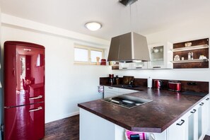 Eine moderne Küche mit einer zentralen Kochinsel, Edelstahlgeräten und einem roten Kühlschrank.