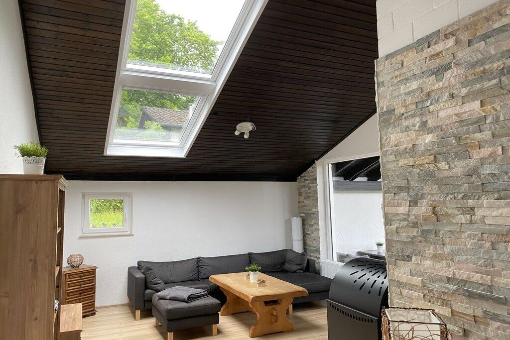 A modern living room with a sectional sofa, a wooden coffee table, and a stone accent wall.