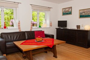 Un salon comprenant un canapé, une table basse en bois, un téléviseur et un meuble.