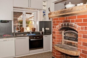 Eine Küche mit einem integrierten Backofen aus Ziegelsteinen, einem Geschirrspüler und einem Fenster.