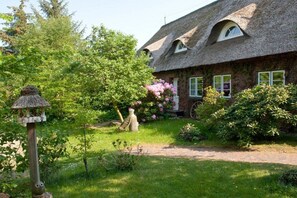 Ein traditionelles Haus mit einem Reetdach und einem Gartenweg, der zum Eingang führt.