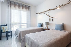 A bedroom with two beds, a chair, a lamp, and a branch decoration. - Two Brothers Home 3 (Vila Real de Santo António)