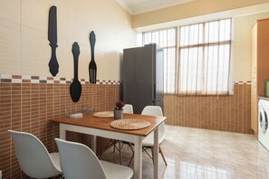 Een eetgedeelte met een houten tafel, witte stoelen en een televisie aan de muur.