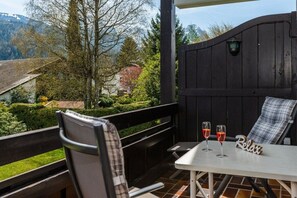 A patio with a table and chairs, two glasses of red wine, and a 'Relax' sign. - Holiday apartment with 1 bedroom (Garmisch-Partenkirchen)