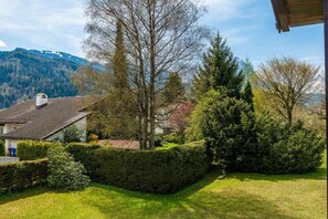 Una propiedad residencial con un césped cuidado, diversidad de árboles y montañas al fondo.