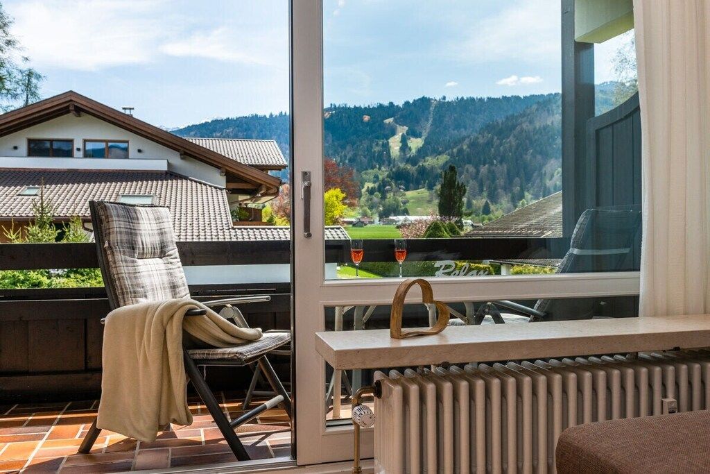 A balcony with a chair, a table, and a view of a mountainous landscape.