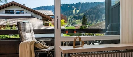 A balcony with a chair, a table, and a view of a mountainous landscape.