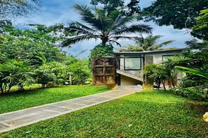 A pathway leading to a modern building with a staircase, surrounded by lush greenery and palm trees. - Niira Mirissa (Mirissa)