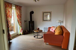 A living room with a sofa, a table, a fireplace, and a lamp. - Holiday apartment with 2 bedrooms (Garmisch-Partenkirchen)