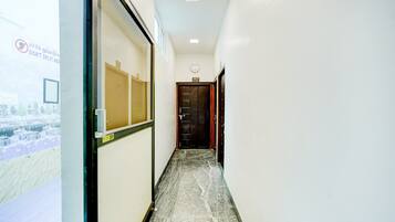 Un corridoio con vista sulla città attraverso una finestra, una porta con la scritta '303 VIP' e un cartello con l'avviso 'NON DIVIDERE'.