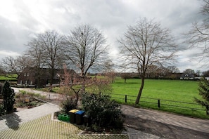 A rural setting with a paved pathway, a green field, and leafless trees. - Cloud (Holiday home Haldern) (Rees)