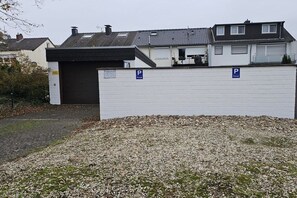 A gated parking area with a gravel driveway leading to a building with a garage. - Holiday apartment on the edge of the forest (Wassenberg)