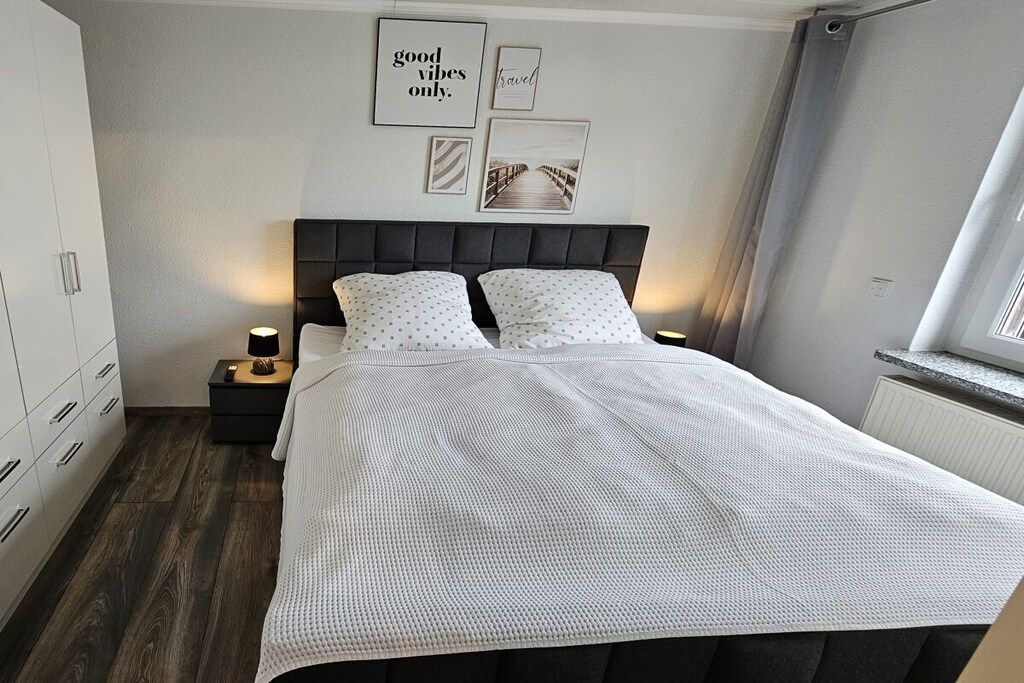 A bedroom with a bed, bedside tables, a wardrobe, and wall art.
