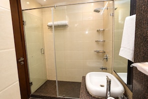 Un baño moderno con ducha envuelta en vidrio, un lavamanos blanco y un espejo.