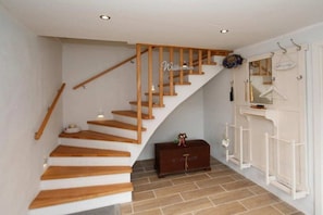 A staircase with wooden steps and a handrail, a white door with a coat rack, and a small chest of drawers. - Holiday apartment with 2 bedrooms (Scheggerott)