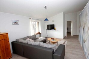 A living room with a sofa, a coffee table, a television, and a wooden cabinet. - Holiday apartment with 2 bedrooms (Scheggerott)