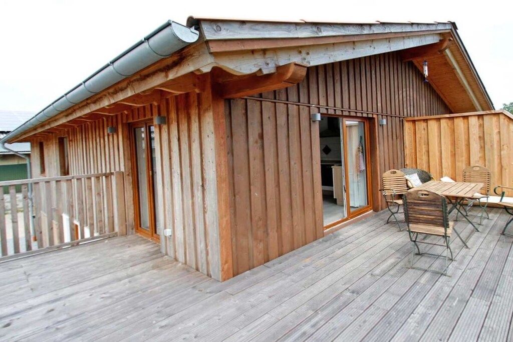 A wooden cabin with a balcony and a table with chairs.