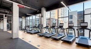 A gym with treadmills, exercise bikes, and a concrete pillar. - Landing Stunning 1bd, Gym, Pool (Nashville)
