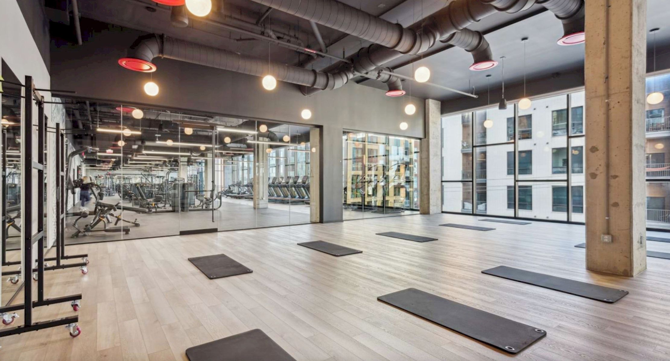 Un gimnasio con colchonetas de ejercicio, máquinas de pesas y cintas de correr.