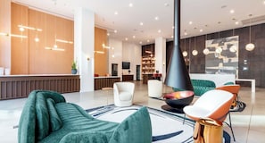 A modern lobby with seating, a reception desk, and a fireplace. - Landing Stunning 1bd, Gym, Pool (Nashville)