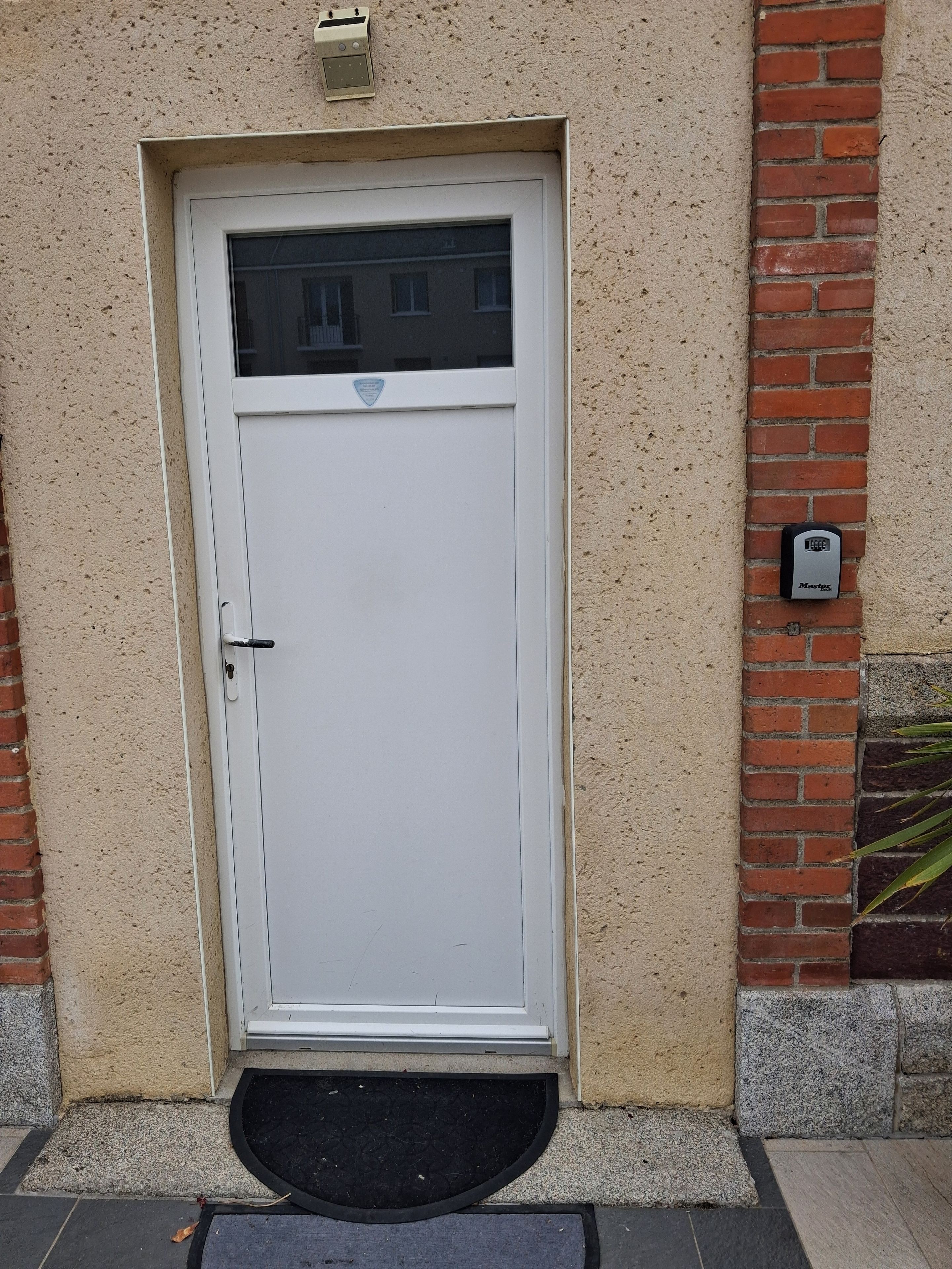 A white door with a peephole, a mail slot, and a small plaque above it.