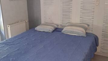 Un dormitorio con una cama, dos almohadas, un radiador y una pared con un diseño vertical.