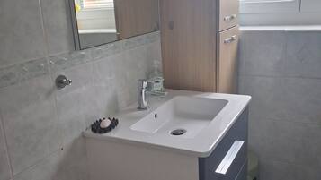 Un baño con un lavabo blanco, un espejo encima y un mueble de madera debajo.