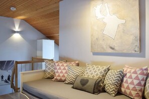 Une pièce chaleureuse avec un plafond en bois, un lit agrémenté d’oreillers à motifs et une œuvre d’art représentant un élan, accrochée au mur.