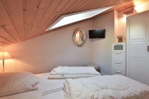 A bedroom with a skylight, a bed, a TV, a dresser, and a mirror. - Holiday apartment with 1 bedroom (Braunlage)