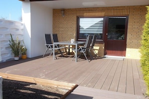 A deck with a table and chairs, a potted plant, and a sliding glass door. - 2 in the periwinkle house (Cuxhaven-Duhnen)