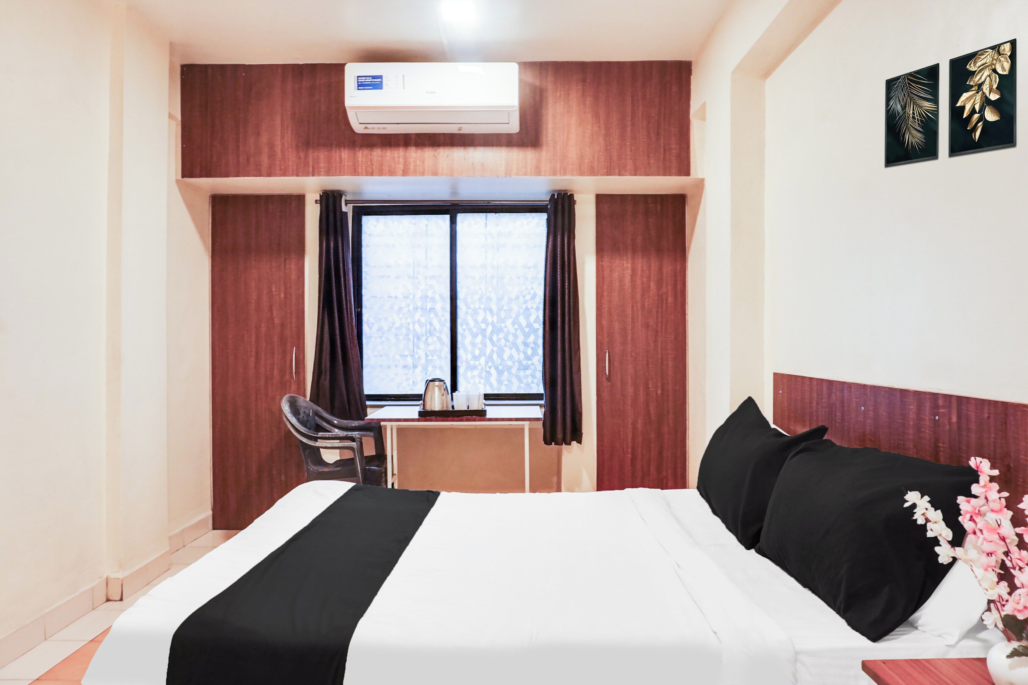 Habitación de hotel con cama, escritorio, silla, aire acondicionado y ventana con cortinas.