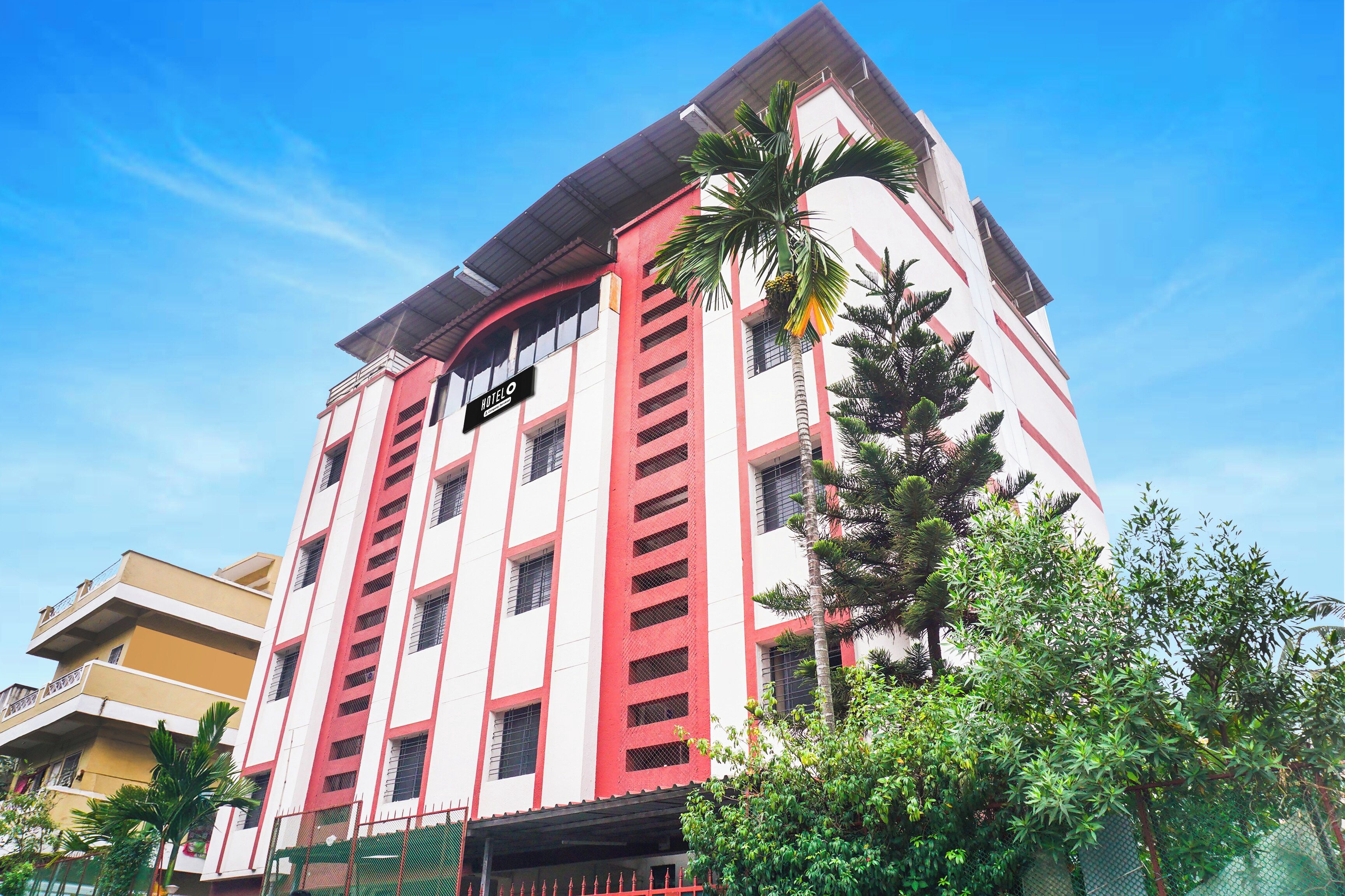 A multi-story hotel with a red and white facade, balconies, and a sign indicating it is a hotel.