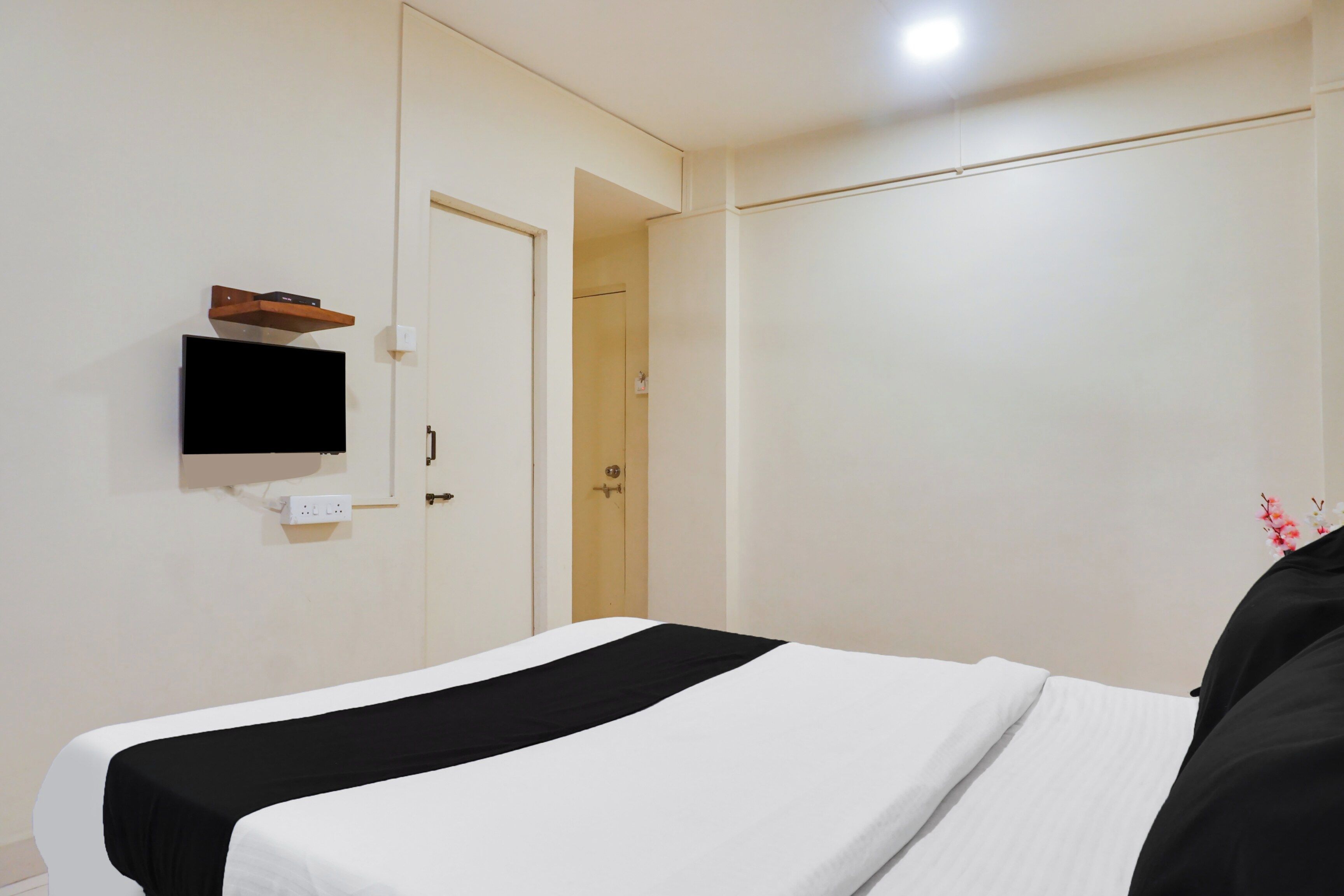 Une chambre d’hôtel avec un lit, un téléviseur fixé au mur et une porte donnant sur une autre pièce.