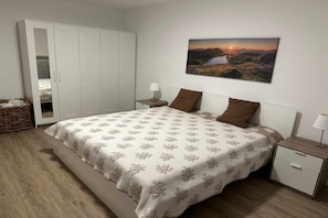 Ein Schlafzimmer mit Bett, Nachttisch, Lampe, Schrank und einem Bild an der Wand.